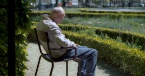 Serene image of an elderly man sitting peacefully in an Amsterdam garden.
