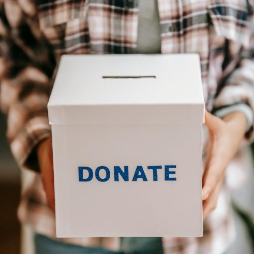 Close-up of a person holding a 'donate' box, encouraging charity and support.